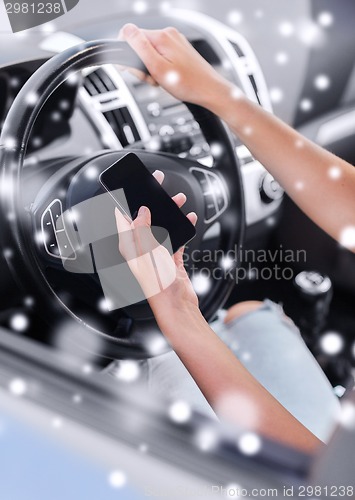 Image of close up of woman with smartphone driving car