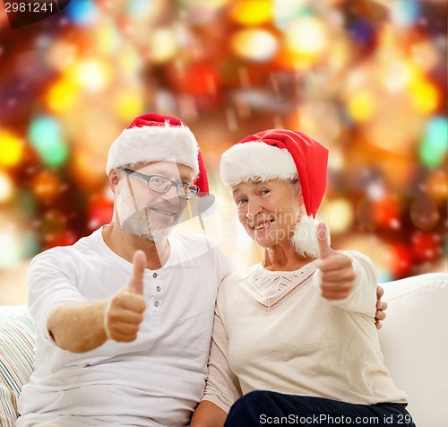 Image of happy senior couple in santa helper hats