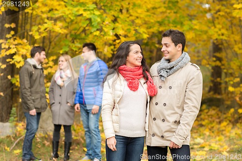 Image of group of smiling men and women in autumn park