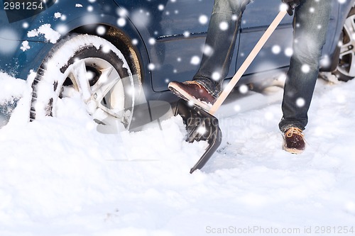 Image of closeup of man digging snow with shovel near car