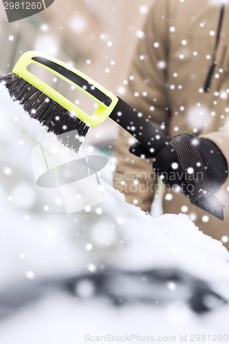 Image of closeup of man cleaning snow from car