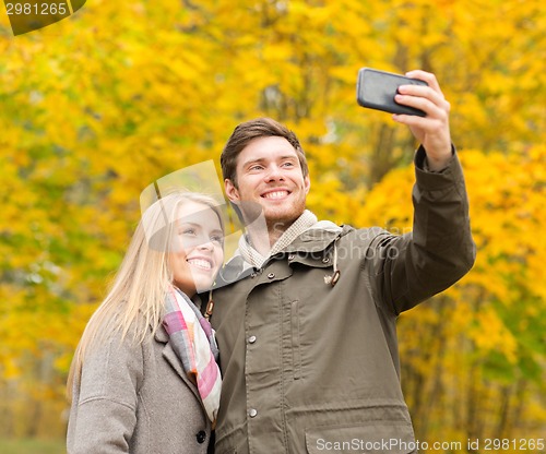Image of smiling couple hugging in autumn park
