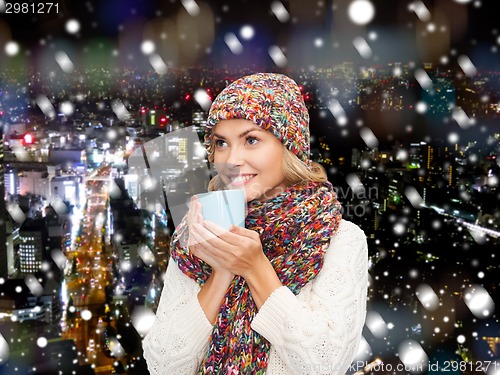 Image of smiling young woman in winter clothes with cup