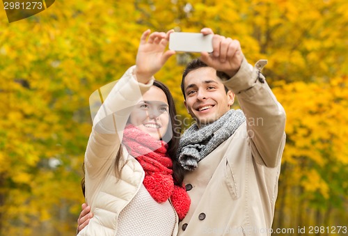 Image of smiling couple hugging in autumn park