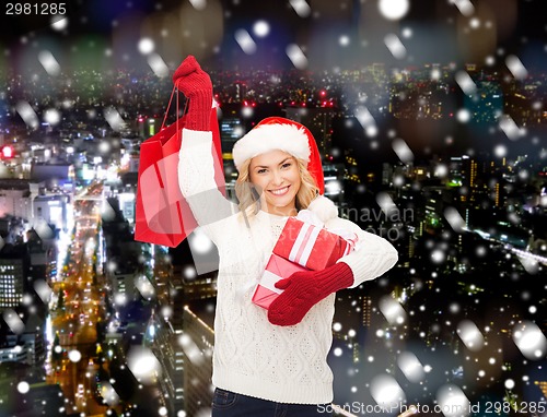 Image of smiling young woman in santa helper hat with gifts