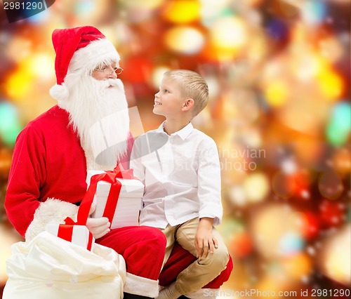 Image of smiling little boy with santa claus and gifts