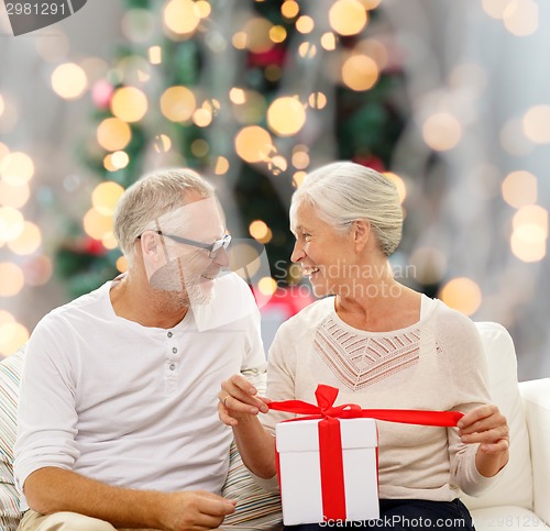 Image of happy senior couple with gift box at home