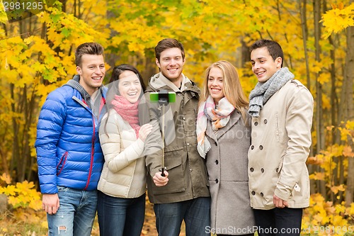 Image of smiling friends with smartphone in city park