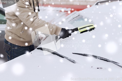 Image of closeup of man cleaning snow from car