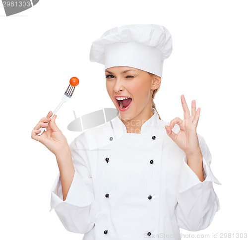 Image of smiling female chef with fork and tomato