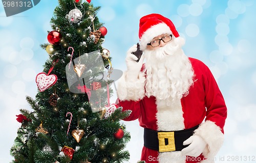 Image of santa claus with smartphone and christmas tree