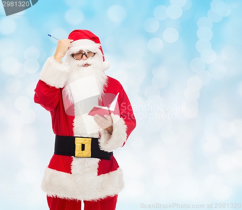 Image of man in costume of santa claus with notepad