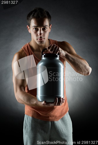 Image of young male bodybuilder holding jar with protein