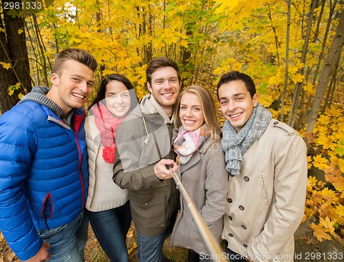 Image of smiling friends with smartphone in city park