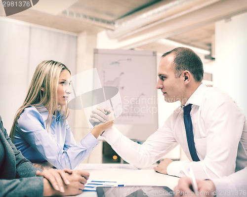 Image of businesswoman and businessman arm wrestling