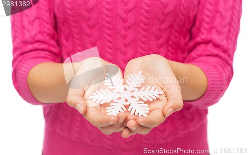 Image of close up of woman in sweater holding snowflake