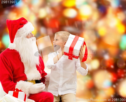 Image of smiling little boy with santa claus and gifts
