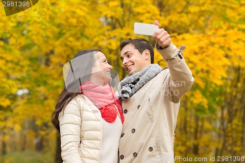 Image of smiling couple hugging in autumn park