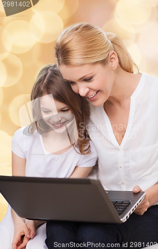 Image of smiling mother and little girl with laptop