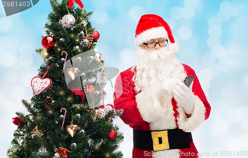 Image of santa claus with smartphone and christmas tree