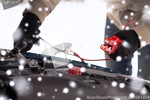 Image of closeup of man under bonnet with starter cables