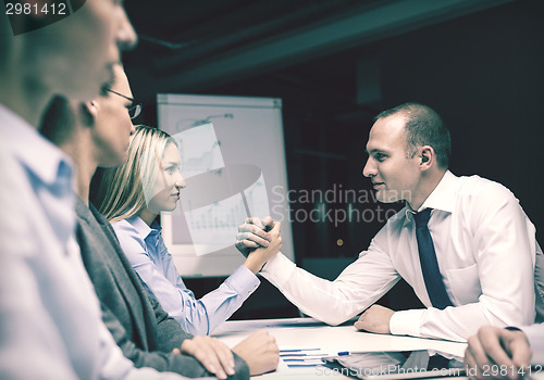 Image of businesswoman and businessman arm wrestling