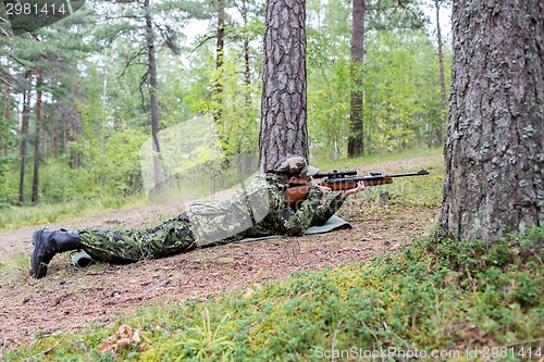 Image of young soldier or hunter with gun in forest