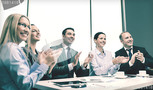 Image of business team with laptop clapping hands