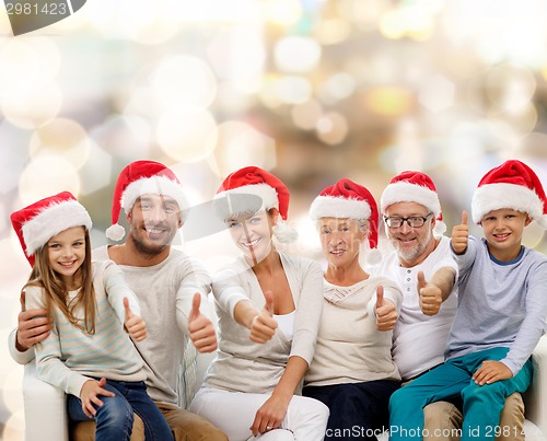 Image of happy family in santa hats showing thumbs up