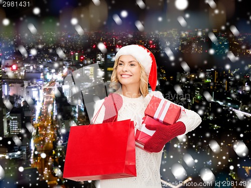 Image of smiling young woman in santa helper hat with gifts