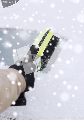 Image of closeup of man cleaning snow from car