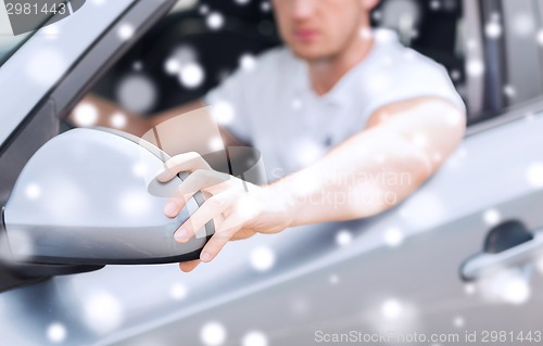 Image of close up of man adjusting car sideview mirror