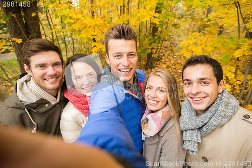Image of group of smiling men and women in autumn park