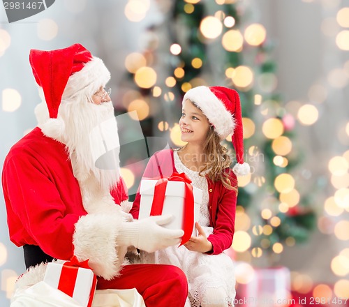 Image of smiling little girl with santa claus and gifts