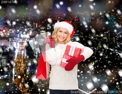 Image of smiling young woman in santa helper hat with gifts