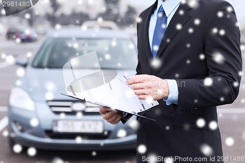 Image of close up of man with clipboard and car documents