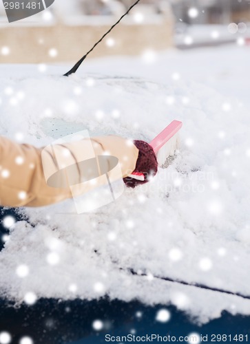 Image of closeup of woman cleaning snow from car