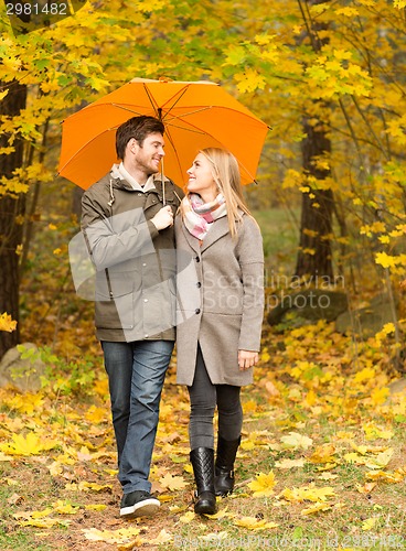 Image of smiling couple with umbrella in autumn park