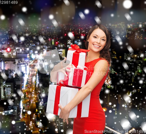 Image of smiling woman in red dress with gift boxes