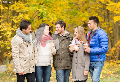 Image of group of smiling friend with coffee cups in park