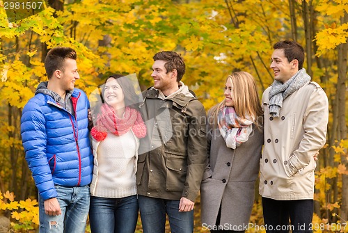 Image of group of smiling men and women in autumn park
