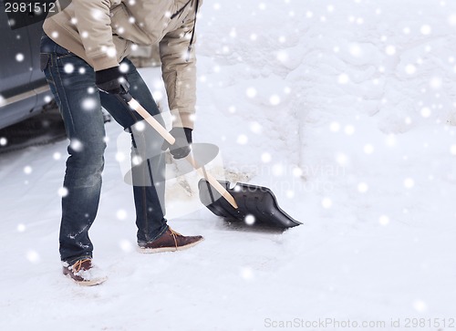 Image of closeup of man digging snow with shovel near car