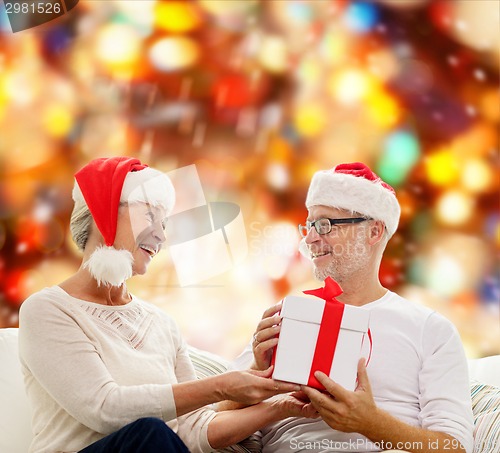 Image of happy senior couple with gift box at home