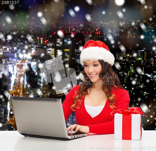 Image of smiling woman with gift box and laptop