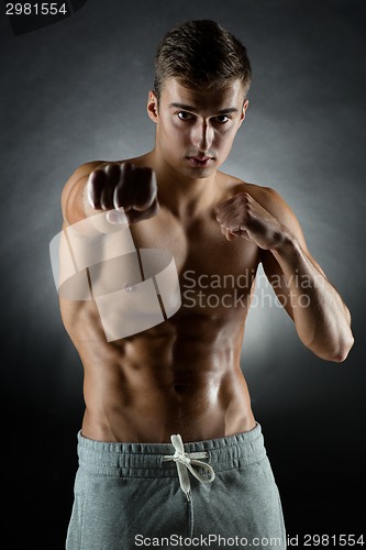 Image of young man on fighting stand over black background