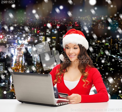 Image of smiling woman with credit card and laptop