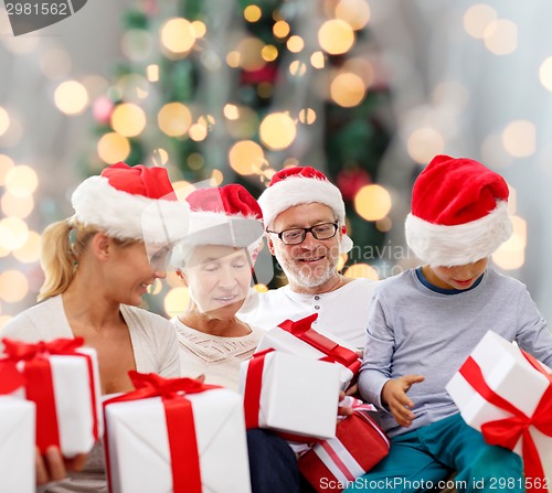 Image of happy family in santa helper hats with gift boxes