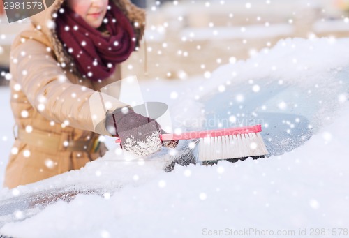 Image of closeup of woman cleaning snow from car