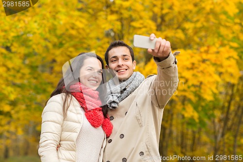 Image of smiling couple hugging in autumn park