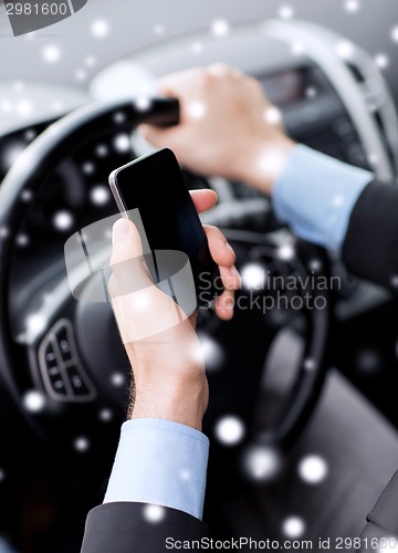 Image of close up of man using smartphone while driving car